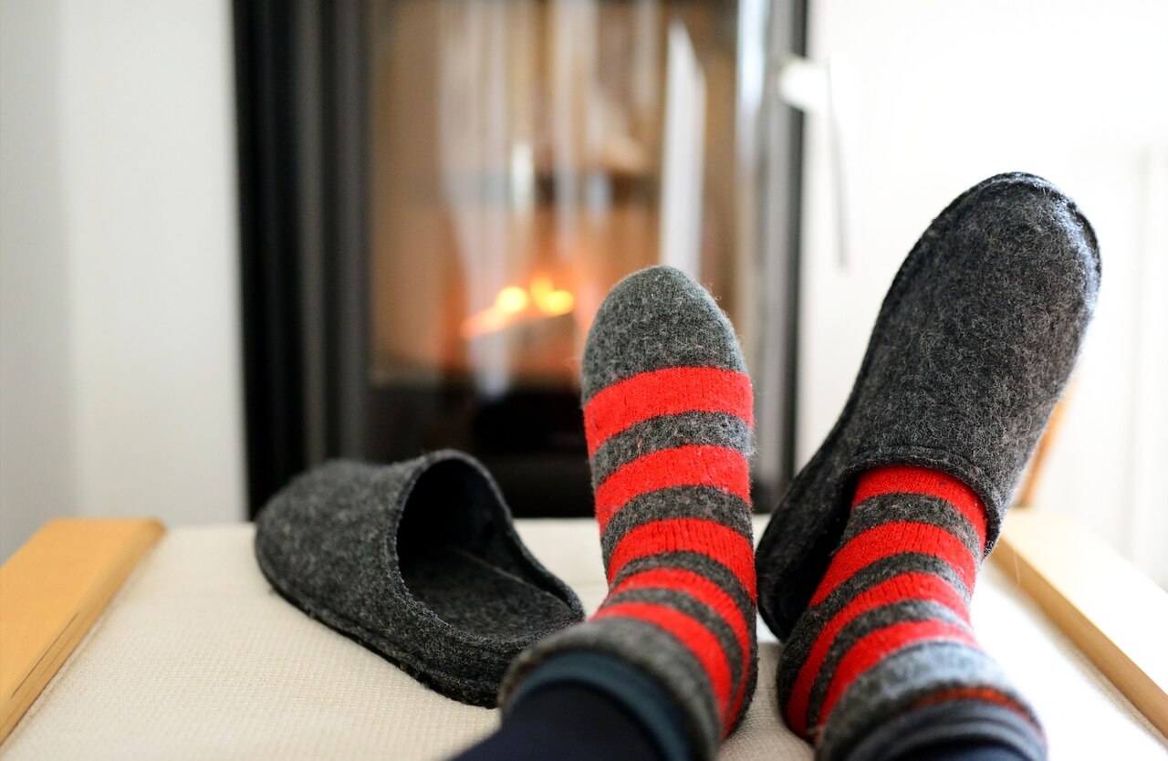 Pieds dans des bas et des pantoufles devant un feu